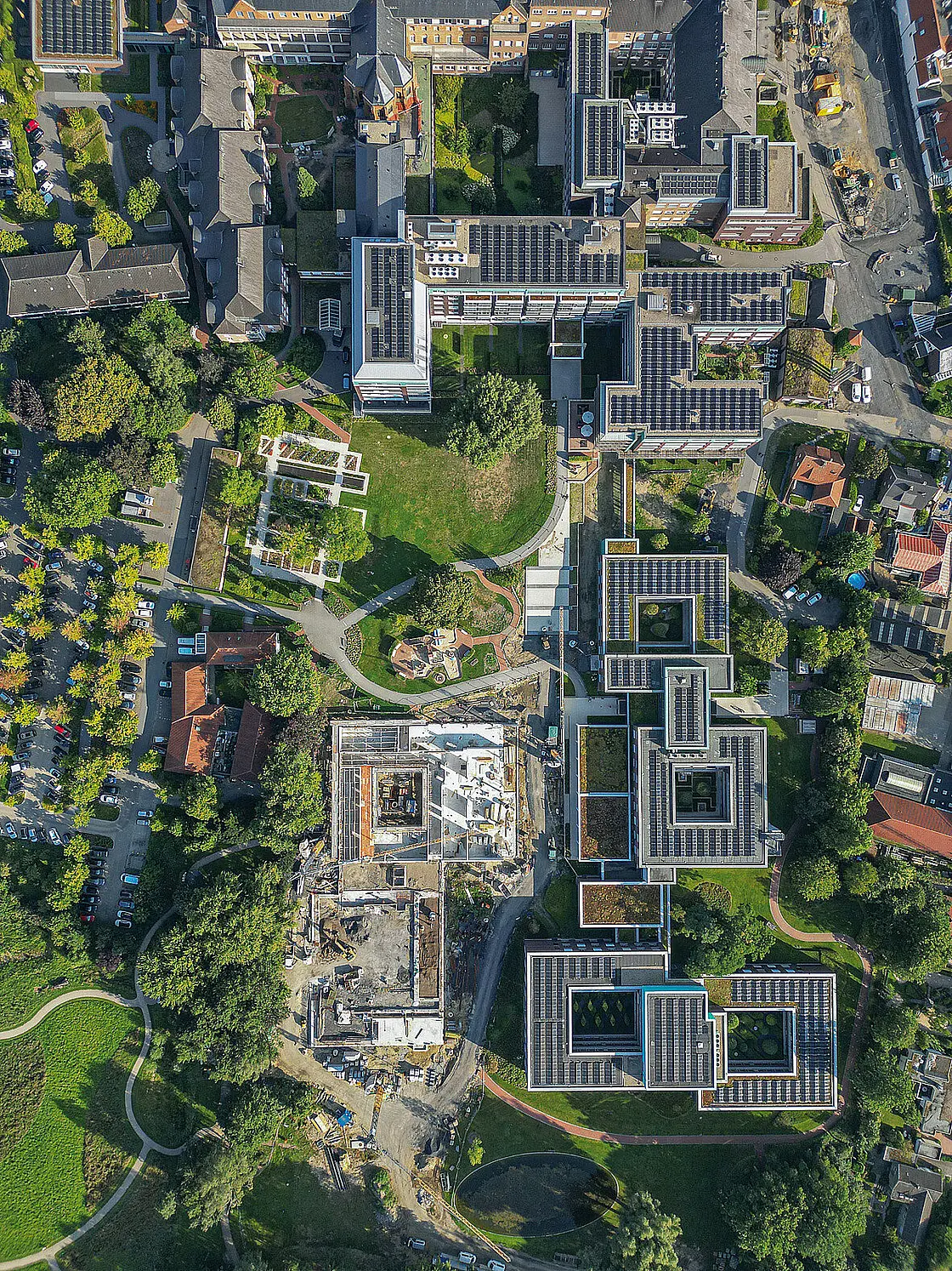 Luftaufnahme des Klinikgeländes mit begrünten Flächen und Photovoltaikanlagen auf mehreren Gebäuden.