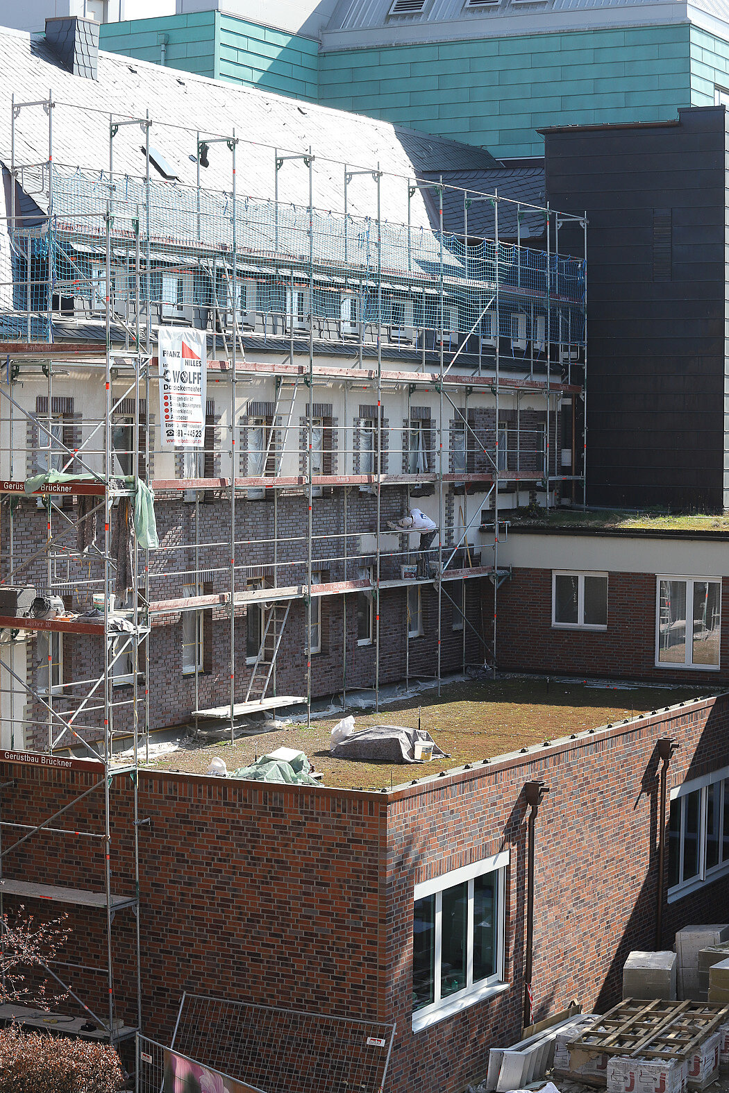 Gebäudefassade während energetischer Sanierungsarbeiten mit Baugerüst und gesicherter Arbeitsfläche.