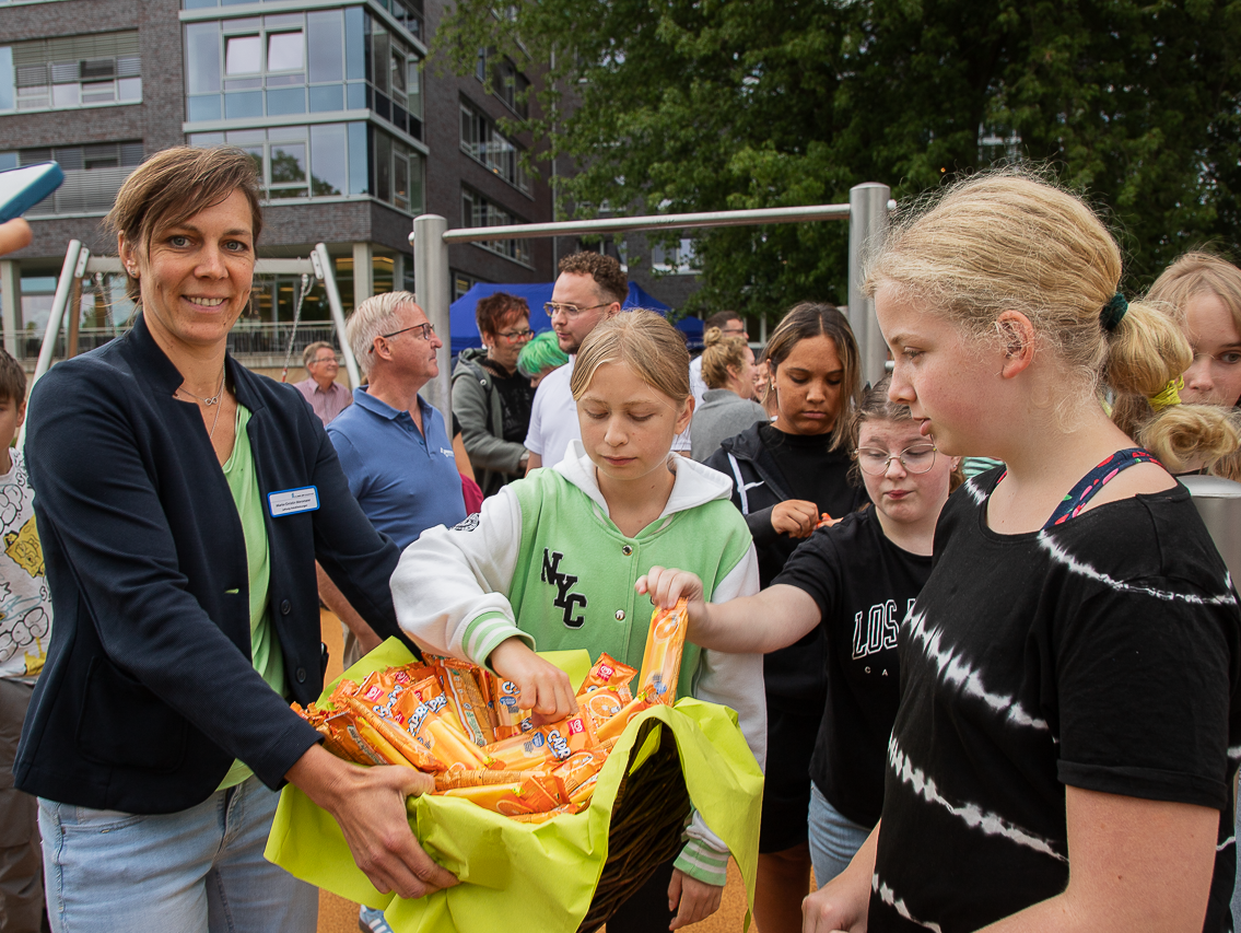 Eine Frau hält Kindern einen Korb mit Eis hin, die Kinder greifen erfreut in den Korb.
