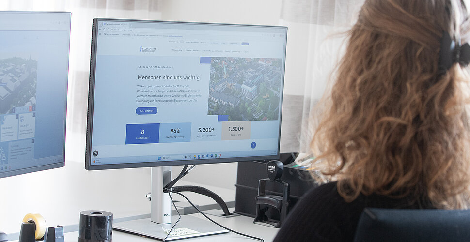 Eine Frau sitzt vor einem PC Bildschirm, geöffnet ist die neue Internetseite.