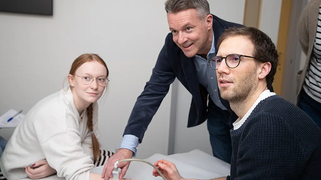 Ein Mädchen lässt ihre Finger von zwei Männern schallen, alle schauen auf einen Bildschirm mit den Ultraschallbildern.